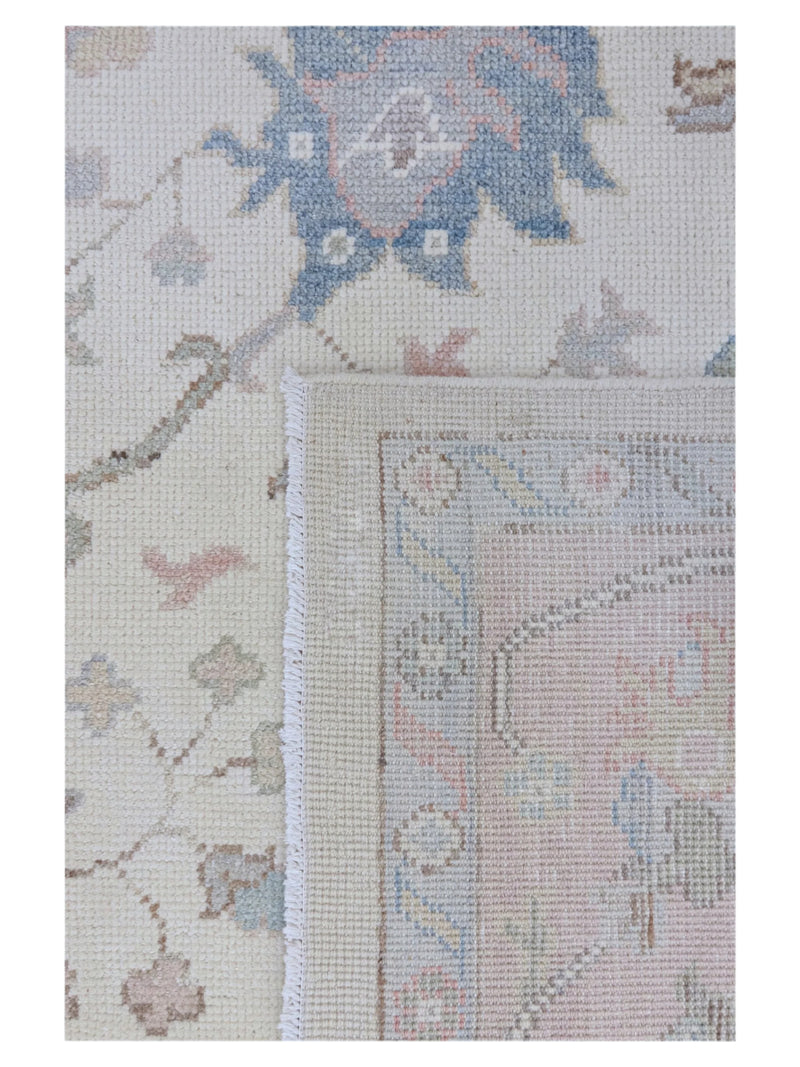 Close-up of a floral patterned rug with a beige and blue color scheme.